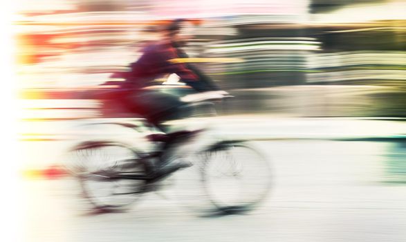 Cyclist on the city roadway in motion blur. Vintage filter with intentional color shift