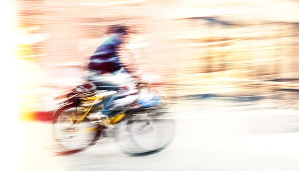 Cyclist on the city roadway in motion blur. Vintage filter with intentional color shift