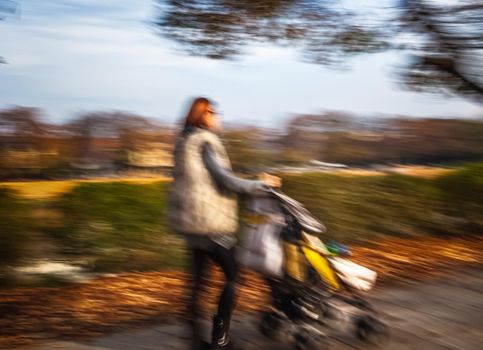 Mother with small children and a pram walking down the street. Intentional motion blur