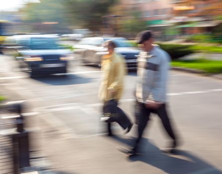 Group of people crossing the street at a crosswalk. Intentional motion blur
