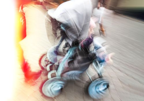 Mother with small child and a pram walking down the street. Intentional motion blur