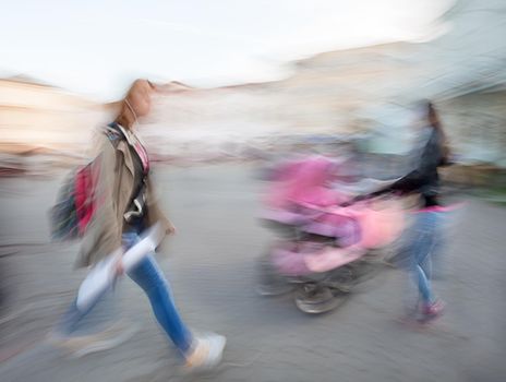 The abstract image of a girl hurrying about their business, and women with a baby in a stroller. Intentional motion blur