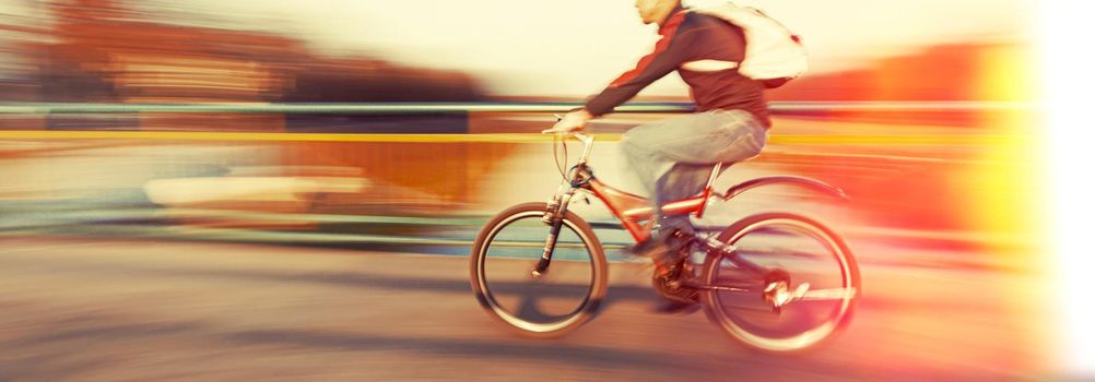 Abstract blurred image of cyclist on the city roadway. Intentional motion blur. Vintage filter with intentional color shift