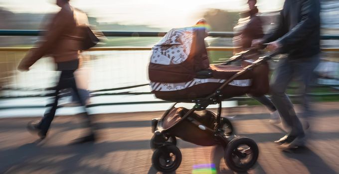 Man with small child and a pram walking down the street. Intentional motion blur