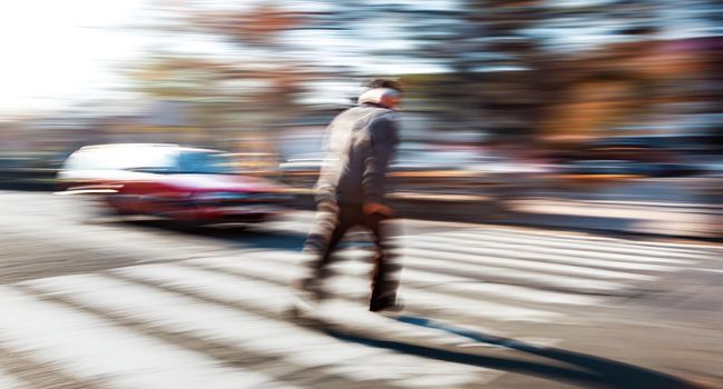 Dangerous situation on zebra crossing. An elderly man runs across the road in front of the car. Intentional motion blur. 