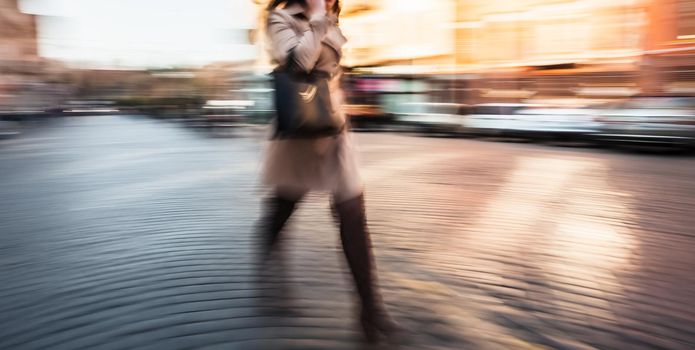 Abstract image of a young woman talking on a cell phone in a hurry. Intentional motion blur