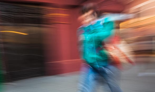 Abstract image of a young woman talking on a cell phone in a hurry. Intentional motion blur