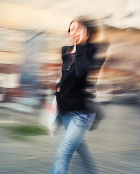 Abstract image of a young woman talking on a cell phone in a hurry. Intentional motion blur