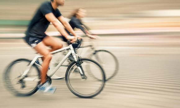 Young man and woman riding bicycles on a city street.  Intentional motion blur