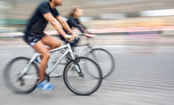 Young man and woman riding bicycles on a city street.  Intentional motion blur