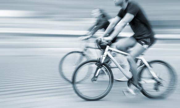 Young man and woman riding bicycles on a city street.  Intentional motion blur
