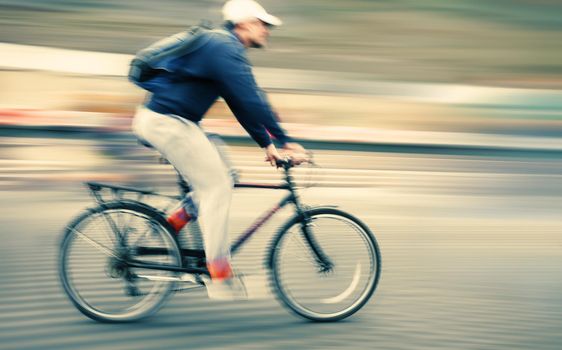 Abstract image of cyclist on the city roadway. Intentional motion blur and color shift