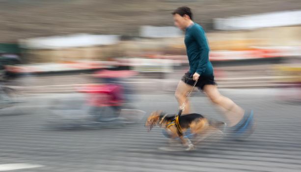 Man runs with his dog outside. Intentional motion blur
