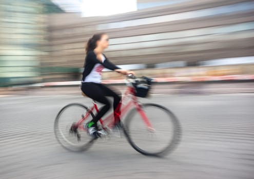 Girl cyclist in traffic on the city roadway. Intentional motion blur