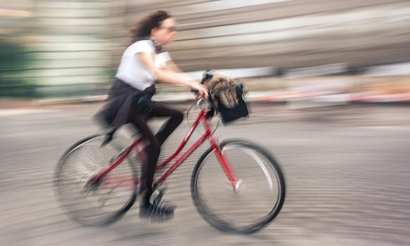 Girl cyclist in traffic on the city roadway. Intentional motion blur