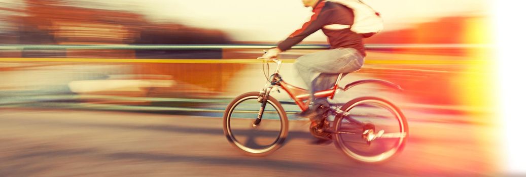 Abstract blurred image of cyclist on the city roadway. Intentional motion blur. Vintage filter with intentional color shift