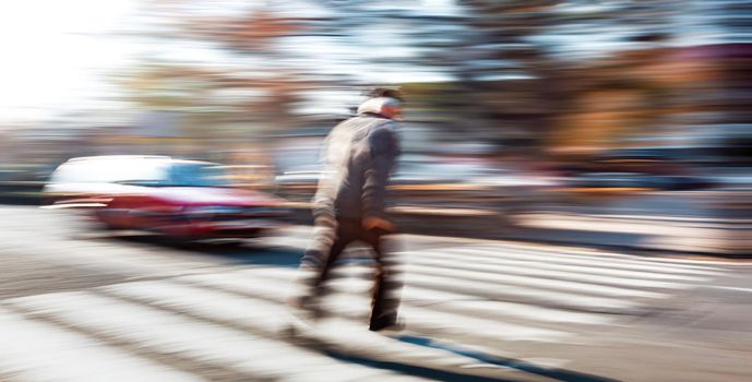 Dangerous situation on zebra crossing. An elderly man runs across the road in front of the car. Intentional motion blur. 