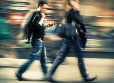 Hot day in the city. Man and woman talking on a cell phone in a hurry. Intentional motion blur and color shift
