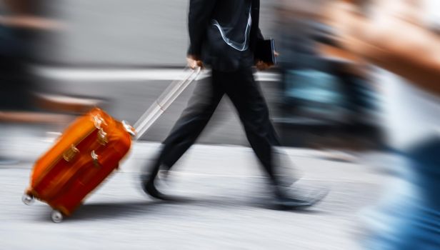 Businessman with a red suitcase in a hurry. Intentional motion blur