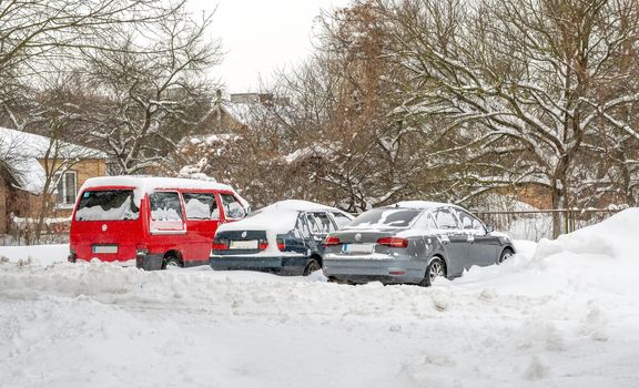 Lutsk, Ukraine - February 12,2020: Stuck car in snow and ice. City street after blizzard. Buried vehicle in snowdrift. Parking in winter after snowfall. Uncleaned road. Record-breaking amounts of snow