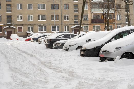 Lutsk, Ukraine - February 12,2020: Stuck car in snow and ice. City street after blizzard. Buried vehicle in snowdrift. Parking in winter after snowfall. Uncleaned road. Record-breaking amounts of snow