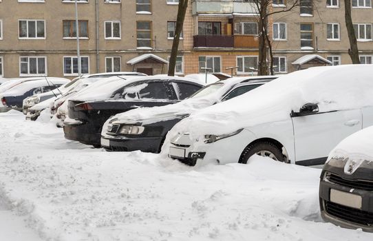 Lutsk, Ukraine - February 12,2020: Stuck car in snow and ice. City street after blizzard. Buried vehicle in snowdrift. Parking in winter after snowfall. Uncleaned road. Record-breaking amounts of snow