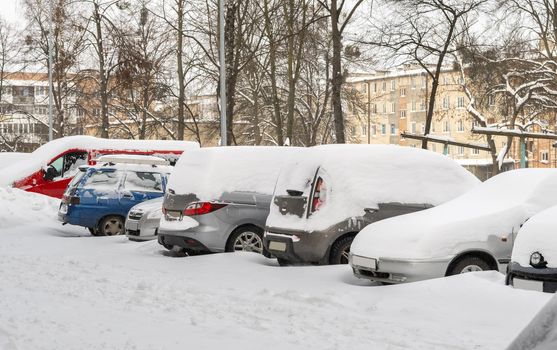 Lutsk, Ukraine - February 12,2020: Stuck car in snow and ice. City street after blizzard. Buried vehicle in snowdrift. Parking in winter after snowfall. Uncleaned road. Record-breaking amounts of snow