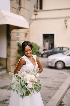 African-American bride in white dress and long veil. With a lush bouquet of the bride in her hands. Wedding in Florence, Italy.