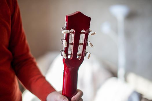 Close-up of a guitar player or a person learning to play an acoustic guitar. Home learning to play a musical instrument