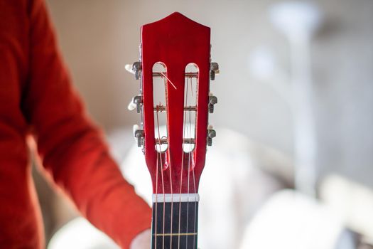 Close-up of a guitar player or a person learning to play an acoustic guitar. Home learning to play a musical instrument