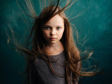 Pretty little girl with disheveled hair on a turquoise background. High quality photo