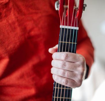 Close-up of a guitar player or a person learning to play an acoustic guitar. Home learning to play a musical instrument