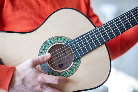 Close-up of a guitar player or a person learning to play an acoustic guitar. Home learning to play a musical instrument