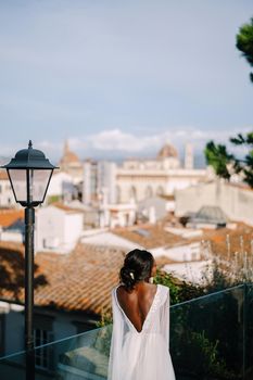 Destination fine-art wedding in Florence, Italy. The African-American bride stands with her back, in a white dress with a large neckline against the backdrop of Florence's urban landscape.