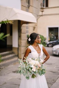 African-American bride in white dress and long veil. With a lush bouquet of the bride in her hands. Wedding in Florence, Italy.