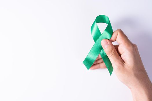 World kidney day, hands holding green ribbon awareness of kidney disease isolated white background.