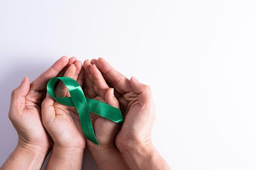 World kidney day, man and woman hands holding green ribbon awareness of kidney disease isolated white background.