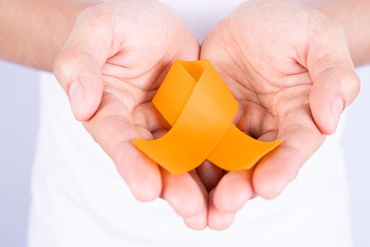 World kidney day, hands holding orange ribbon awareness of kidney disease isolated white background.