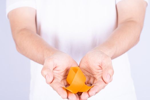 World kidney day, hands holding orange ribbon awareness of kidney disease isolated white background.