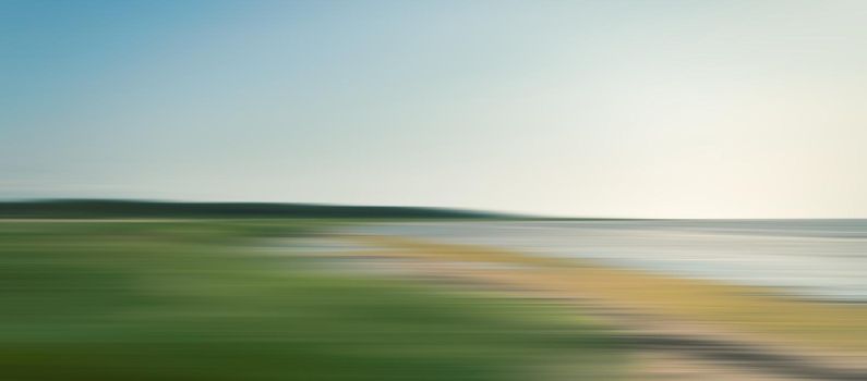 Abstract blurred sea landscape with grass on the beach and blue sky