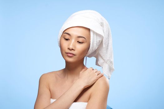 woman of asian appearance bare shoulders towel on head shower rest. High quality photo