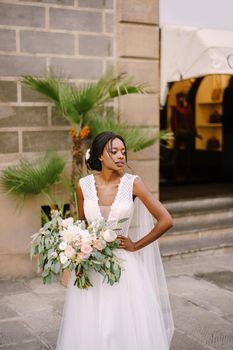 African-American bride in white dress and long veil. With a lush bouquet of the bride in her hands. Wedding in Florence, Italy.