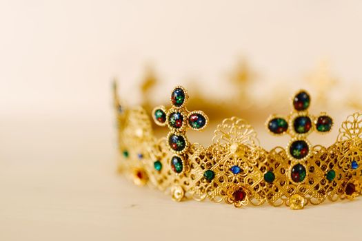 Golden crown encrusted with precious stones and crosses against a white background