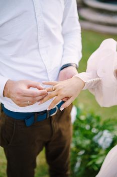 Wedding at an old winery villa in Tuscany, Italy. The groom puts the wedding ring on the brides finger, close-up of hands.