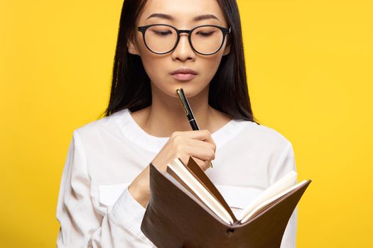 Business woman with notepad in hands elegant style manager yellow background. High quality photo
