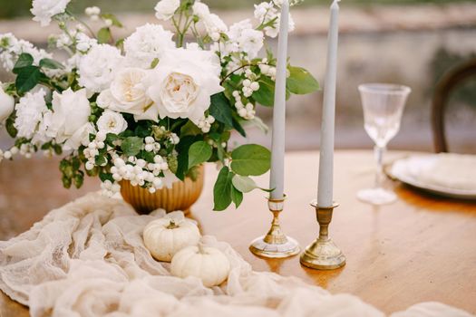 A close-up of a wooden table decorated for a wedding dinner.