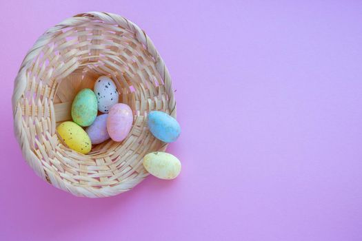 An overturned basket in the shape of a hat with eggs on a pink background. Easter Concept.