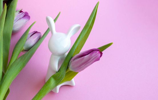 Easter bunny and lilac tulips on pink background, Easter celebration concept.
