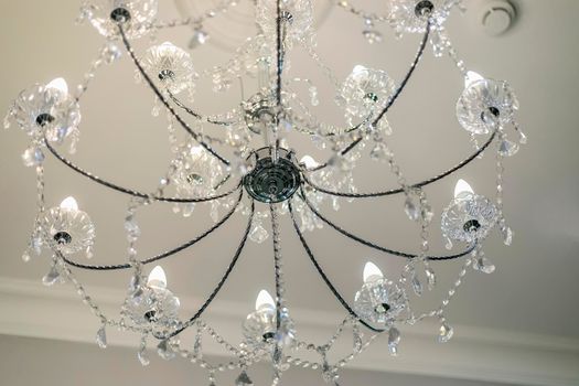 Luxurious crystal chandelier, candle-shaped lamps. Iron base.