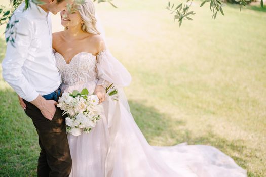 Wedding in Florence, Italy, in an old villa-winery. The wedding couple stands under an olive tree. The bride and groom walk in an olive grove.